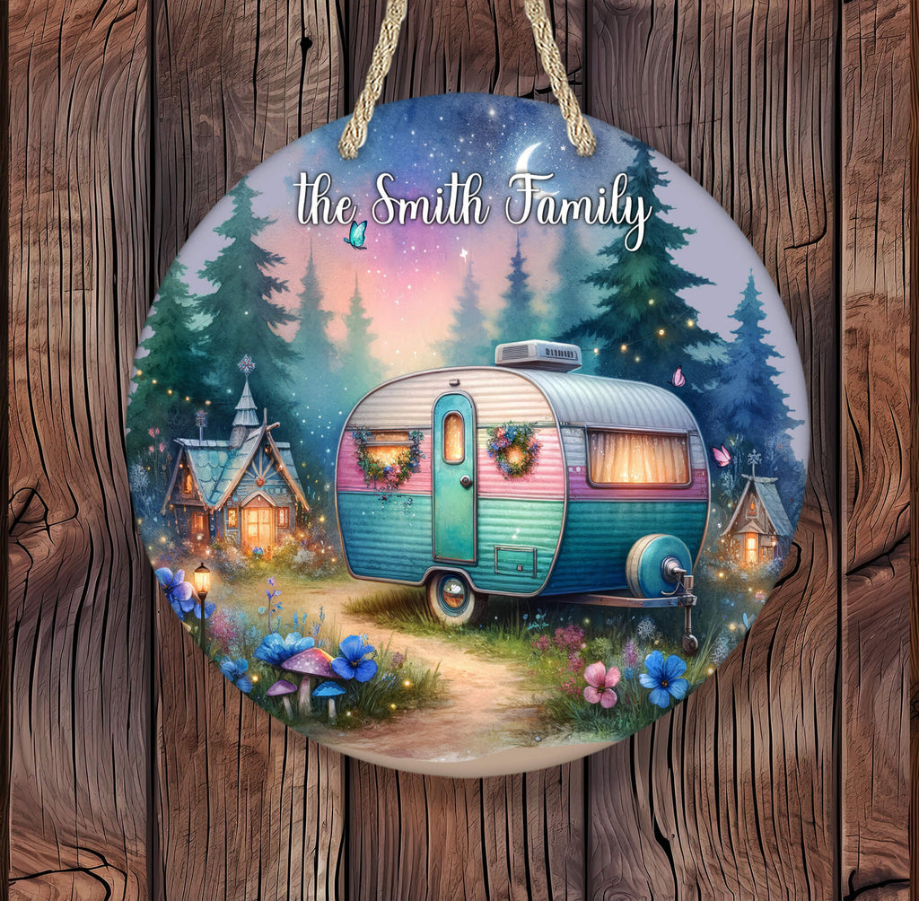 Whimsical hanging round sign featuring a retro teal and pink camper with wreaths on the doors, parked on a glowing forest path under a twilight sky with stars, crescent moon, fireflies, and woodland fairy houses lit warmly in the background - Personalized Kreation