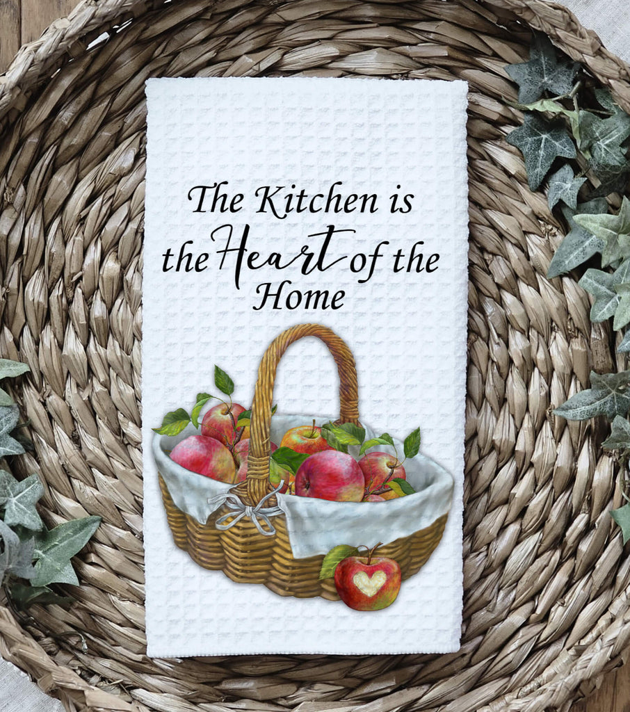 Rustic farmhouse kitchen towel featuring a woven basket filled with fresh red apples adorned with a white linen cloth and a heart The towel reads The Kitchen is the Heart of the Home making it a charming addition to any country kitchen or cozy home - Personalized Kreation