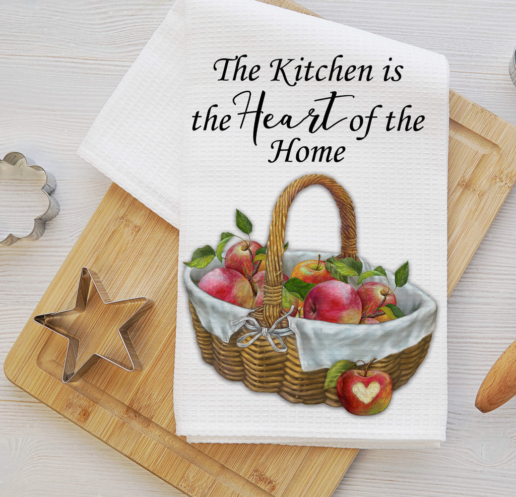 Rustic farmhouse kitchen towel featuring a woven basket filled with fresh red apples adorned with a white linen cloth and a heart The towel reads The Kitchen is the Heart of the Home making it a charming addition to any country kitchen or cozy home - Personalized Kreation