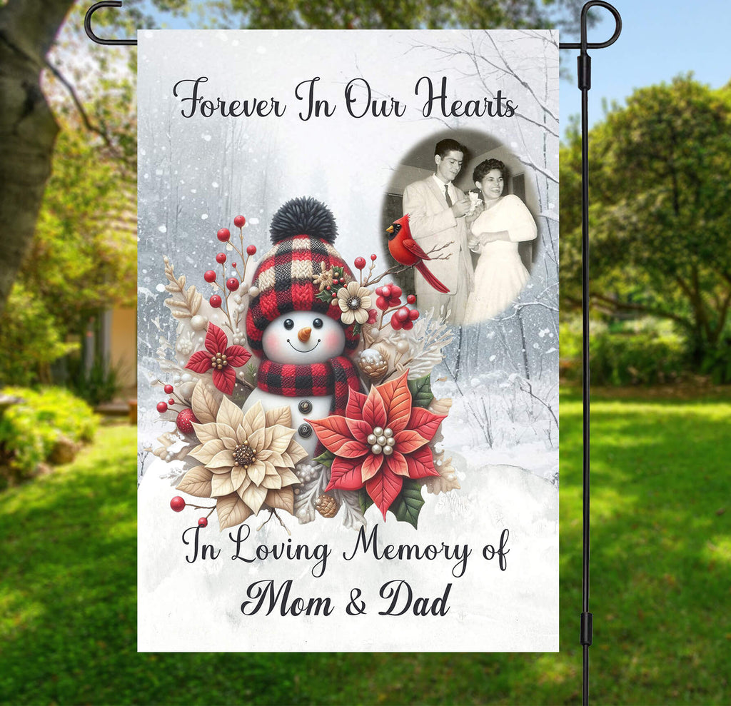 Memorial garden flag with snowman, flowers, and family photo in a garden setting.