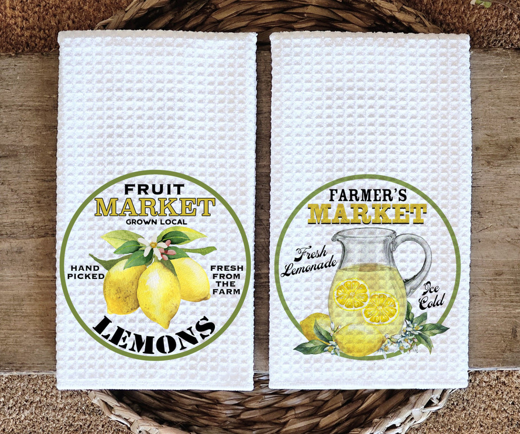 Farmhouse-style kitchen towel set featuring a vintage lemon market design. One towel showcases fresh lemons with 'Fruit Market' text, while the other displays a refreshing lemonade pitcher labeled 'Farmer’s Market.' Perfect for summer kitchen decor, farmhouse styling, and citrus-themed gifts - Personalized Kreation