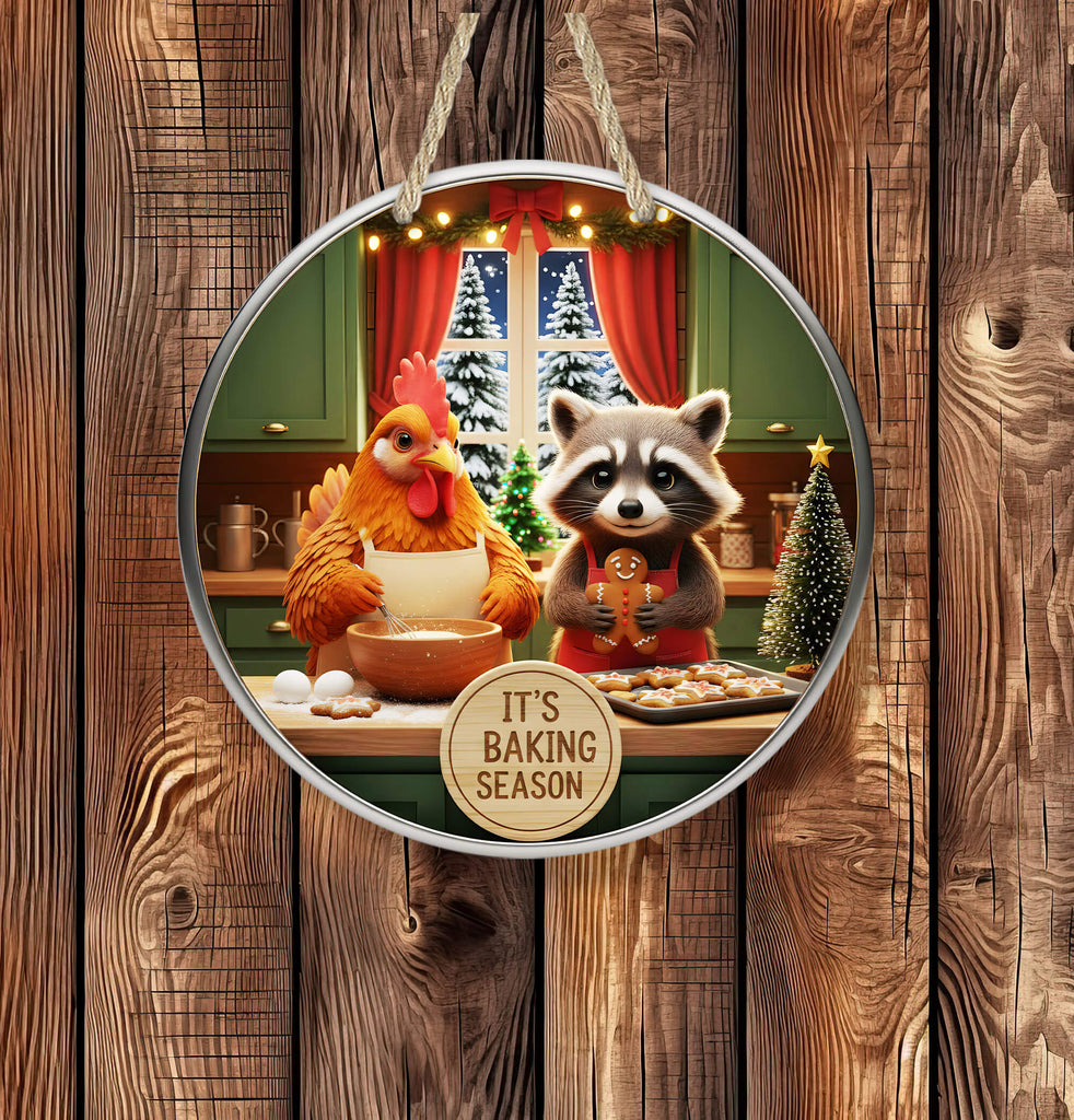 Decorative plate with a chicken and raccoon baking cookies, hanging on a wooden background.