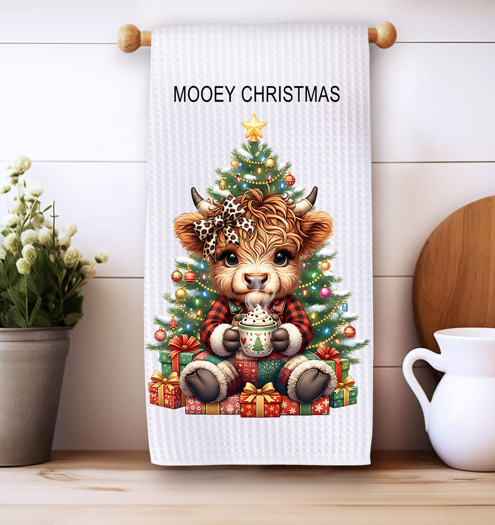 Christmas-themed towel with a cow under a tree, placed on a wooden surface with decorative items.