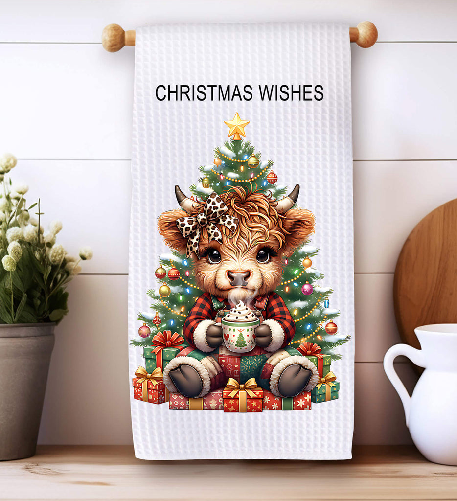 Towel with a Christmas design featuring a cow and tree, placed on a wooden surface with decorative items.