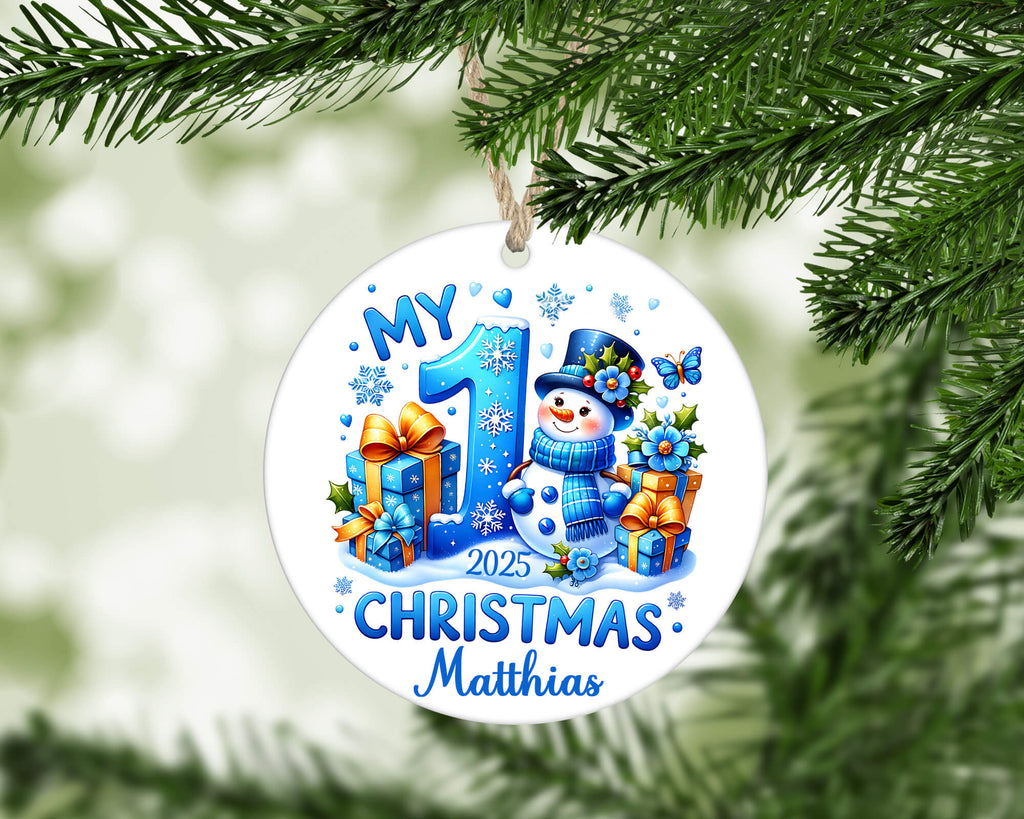 Christmas ornament with snowman and text 'My 1st Christmas 2025' on a green tree branch.