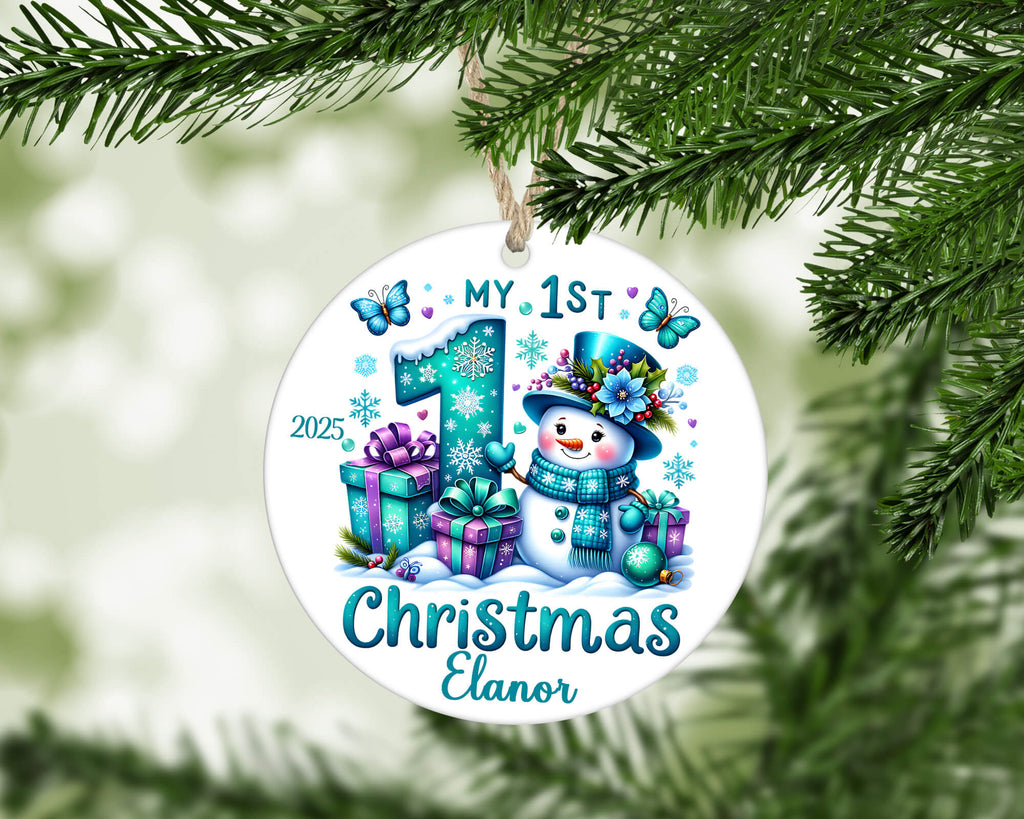 Round Christmas ornament with snowman and presents, featuring 'My 1st Christmas' text, hanging on a tree.