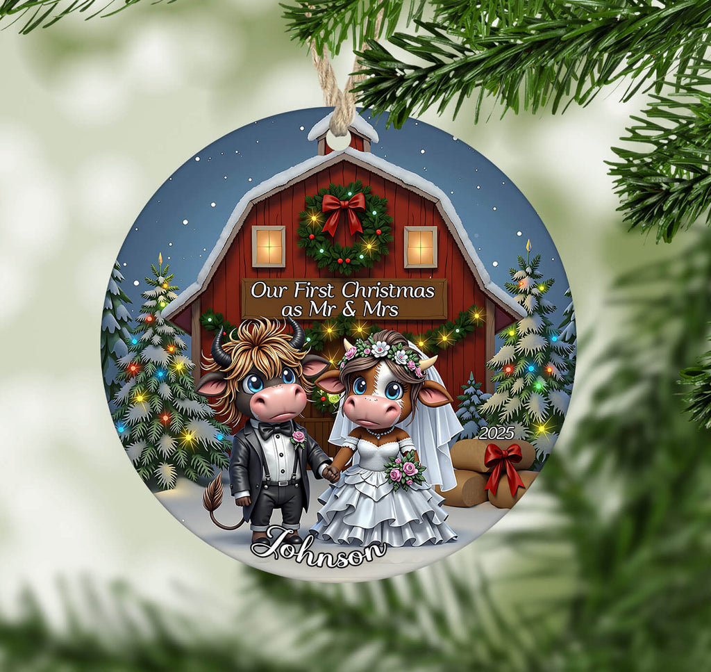 Decorative Christmas ornament with cartoon cows in wedding attire against a barn background.