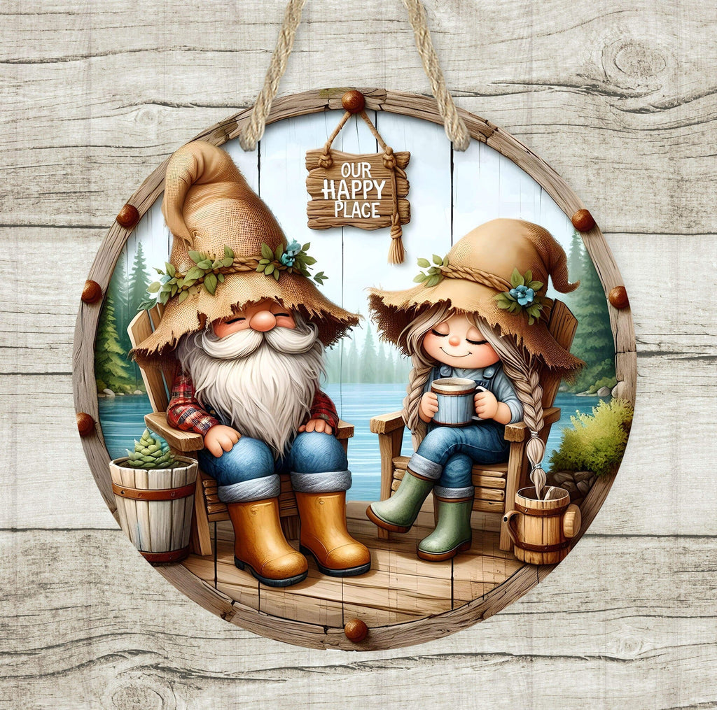 Rustic wooden round sign featuring a cute gnome couple sitting on wooden chairs by a peaceful lake, enjoying a warm drink. The male gnome wears a tan hat with green leaves, plaid shirt, jeans, and yellow boots, while the female gnome wears a matching hat, denim overalls, and green boots. A wooden hanging sign above them reads "Our Happy Place", adding a cozy, farmhouse charm. The background showcases a serene lake, pine trees, and rustic wooden elements, making it perfect for cottagecore, farmhouse, and cab