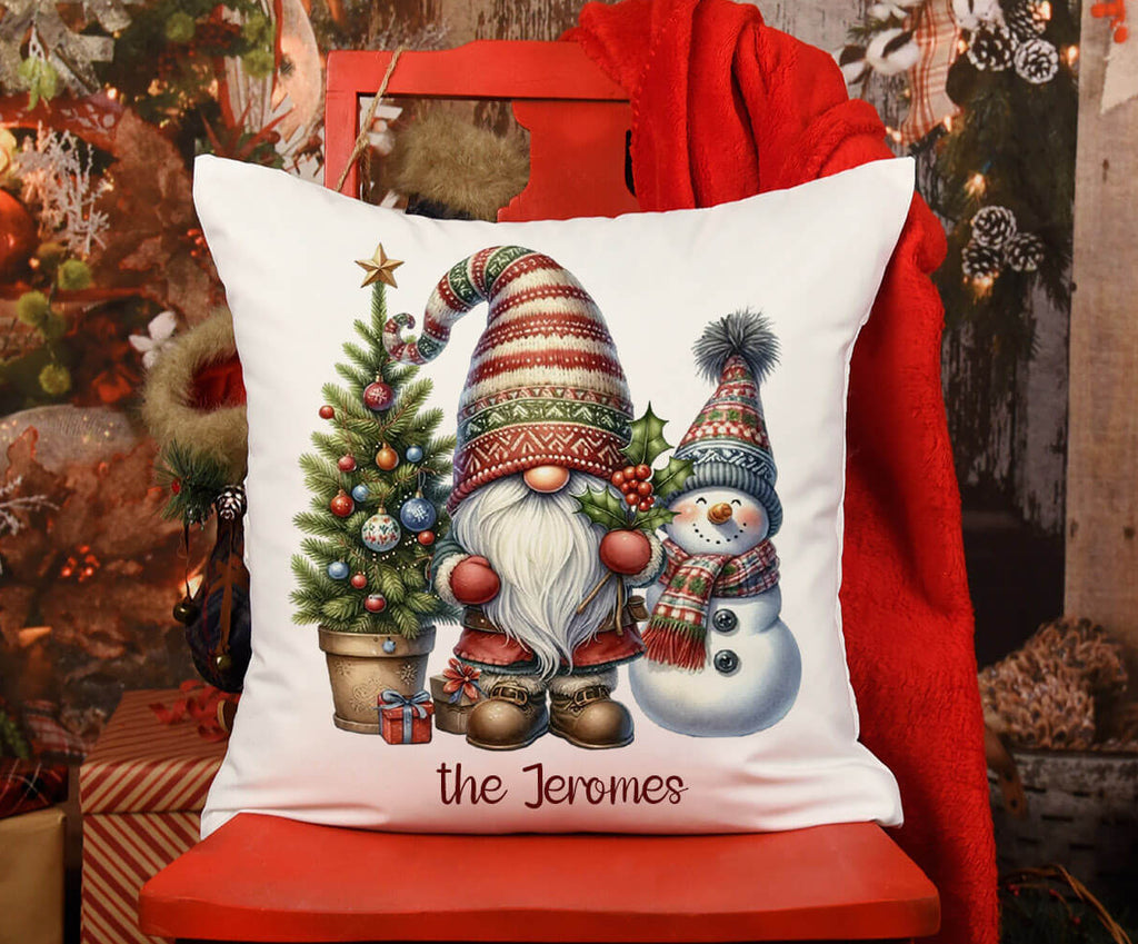 Decorative pillow with Christmas-themed design featuring a gnome and snowman on a red chair.
