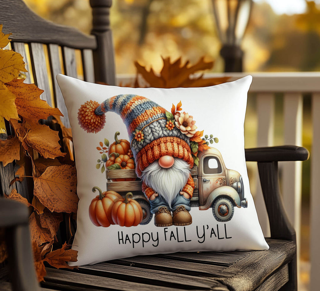 Decorative pillow with a gnome, pumpkins, and a truck design on a wooden chair with autumn leaves.