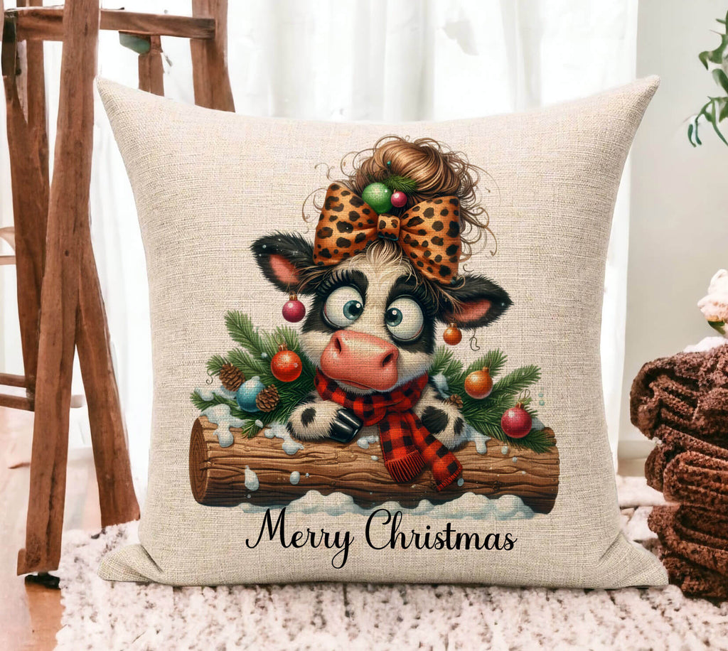 Decorative pillow with a cow illustration and Christmas decorations on a wooden floor.