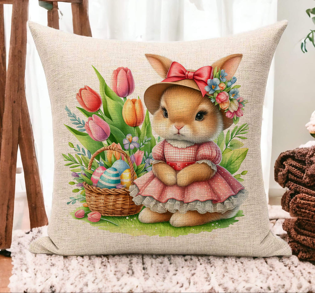 Easter Bunny Pillow featuring a vintage-style bunny in a pink dress and floral hat, sitting beside a pastel Easter basket filled with striped eggs and surrounded by colorful tulips. The design is printed on 18x18 inch beige linen or white canvas, making it a perfect springtime home accent for Easter decor, farmhouse living rooms, and seasonal celebrations - Personalized Kreation