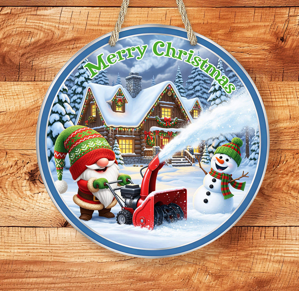 Circular Christmas ornament with Santa Claus using a snow blower and a snowman, set against a snowy village background.