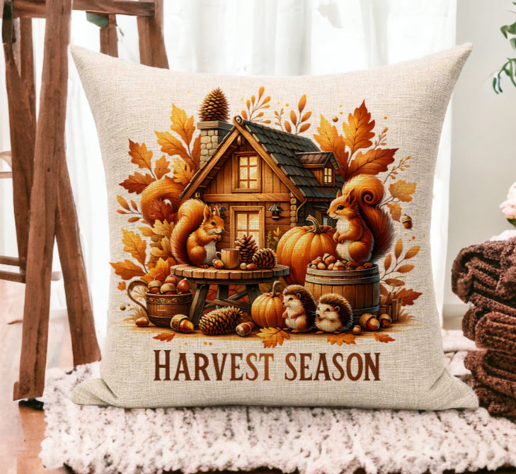 Decorative pillow with 'Harvest Season' design featuring a cabin, pumpkins, and autumn elements on a white background.