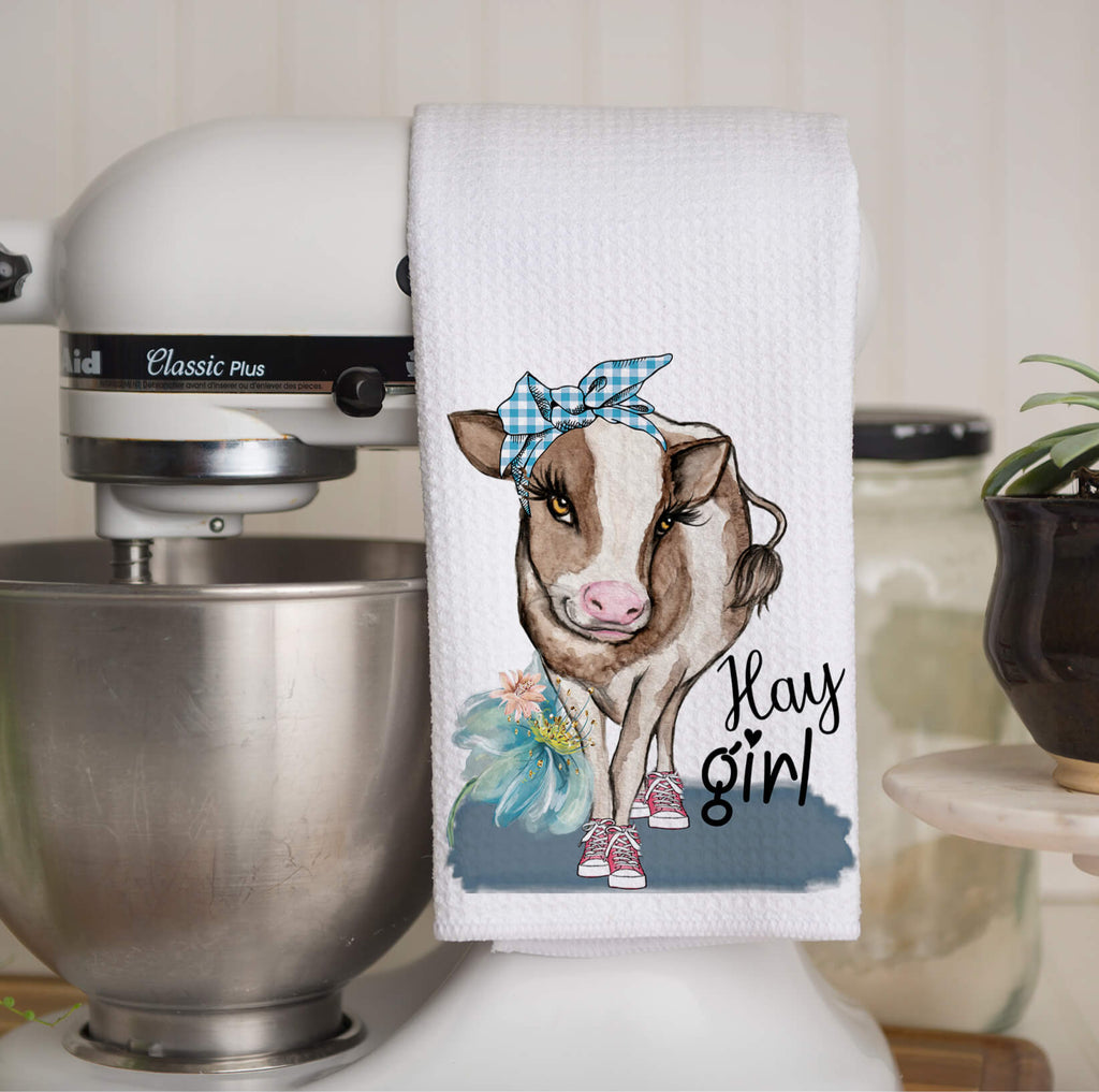 Farmhouse cow kitchen towel featuring a cute cow wearing a blue bandana and sneakers with "Hay Girl" text, perfect for rustic country decor and farmhouse kitchen style. Made from high-quality absorbent fabric, ideal for drying dishes or decorative use - Personalized Kreation