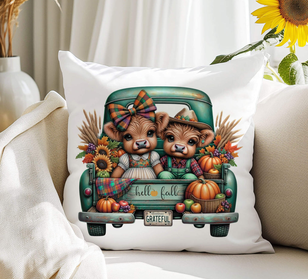Decorative pillow with highland cows in a truck and fall-themed design on a surface.