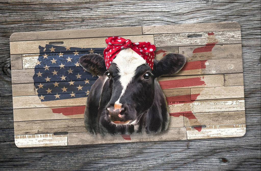 Rustic patriotic cow license plate with USA flag background – farmhouse-style car tag, western truck decor, and country barnyard auto accessory for cow lovers