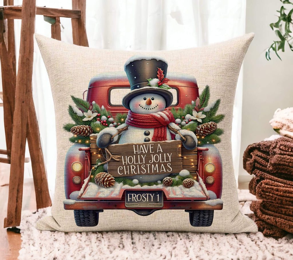 Decorative pillow with a Christmas design featuring a snowman and vintage truck on a wooden floor.