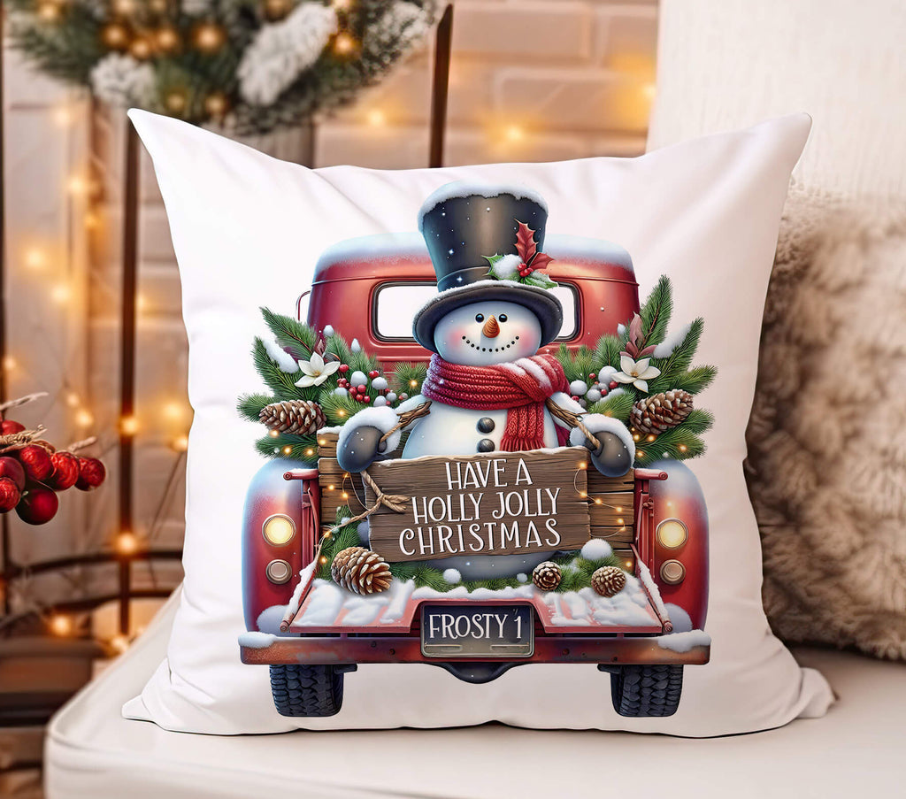 Decorative pillow with a Christmas design featuring a snowman in a truck and festive text.