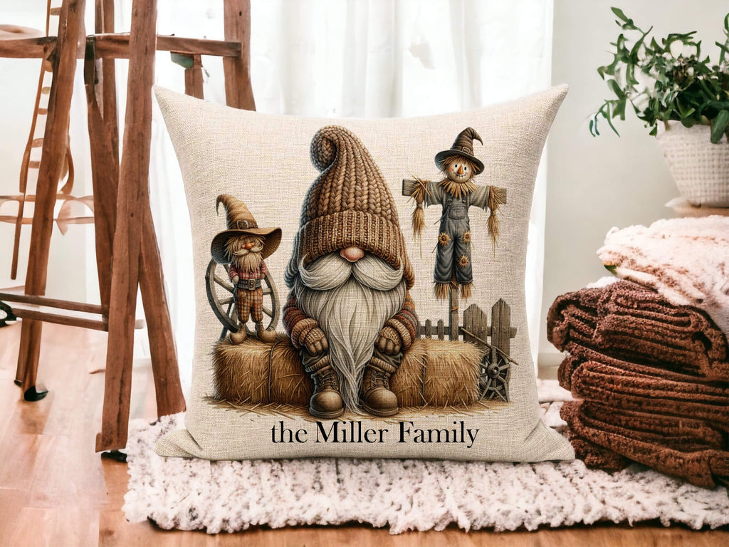 Decorative pillow with gnomes and scarecrow design on a wooden floor.