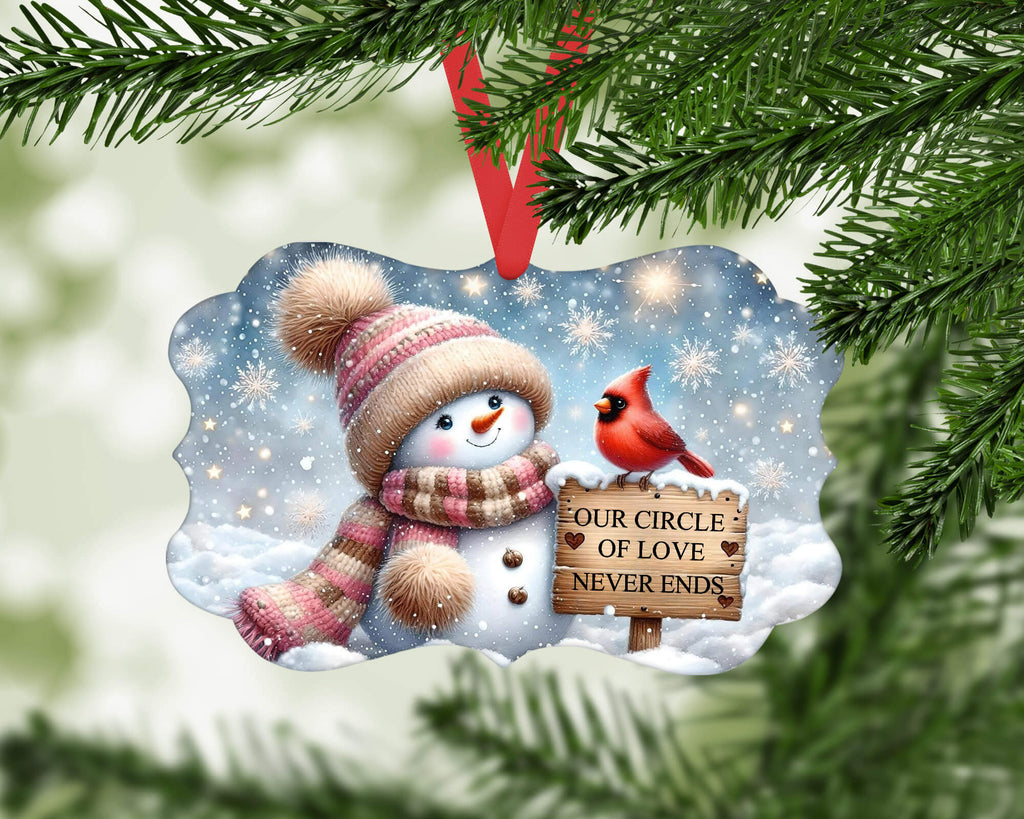 Christmas ornament with snowman and cardinal on a snowy background, hanging from a tree.