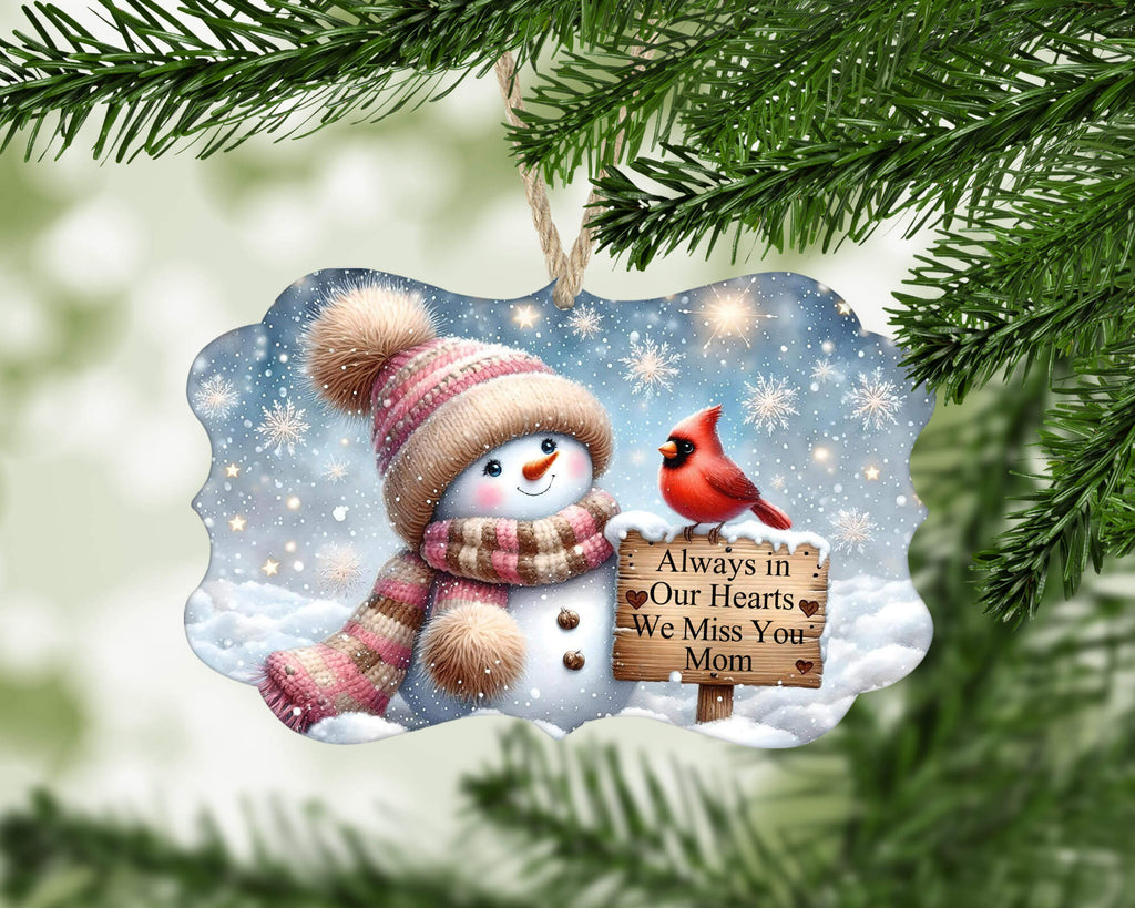 Christmas ornament with snowman, cardinal, and sign 'Always in Our Hearts We Miss You Mom' on a snowy background.