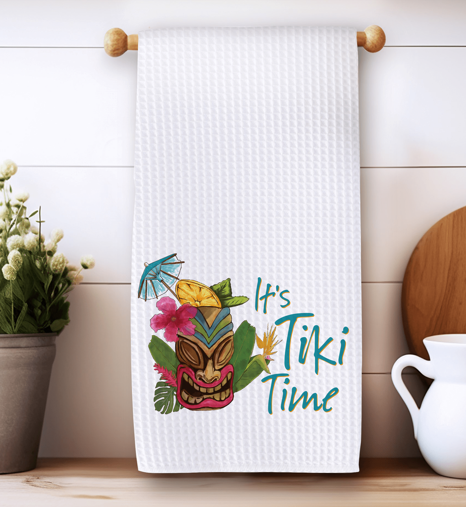 It's Tiki Time kitchen towel featuring a vibrant tiki mask design with tropical flowers and cocktail umbrella, perfect for tiki bar décor, luau parties, and summer kitchen accents