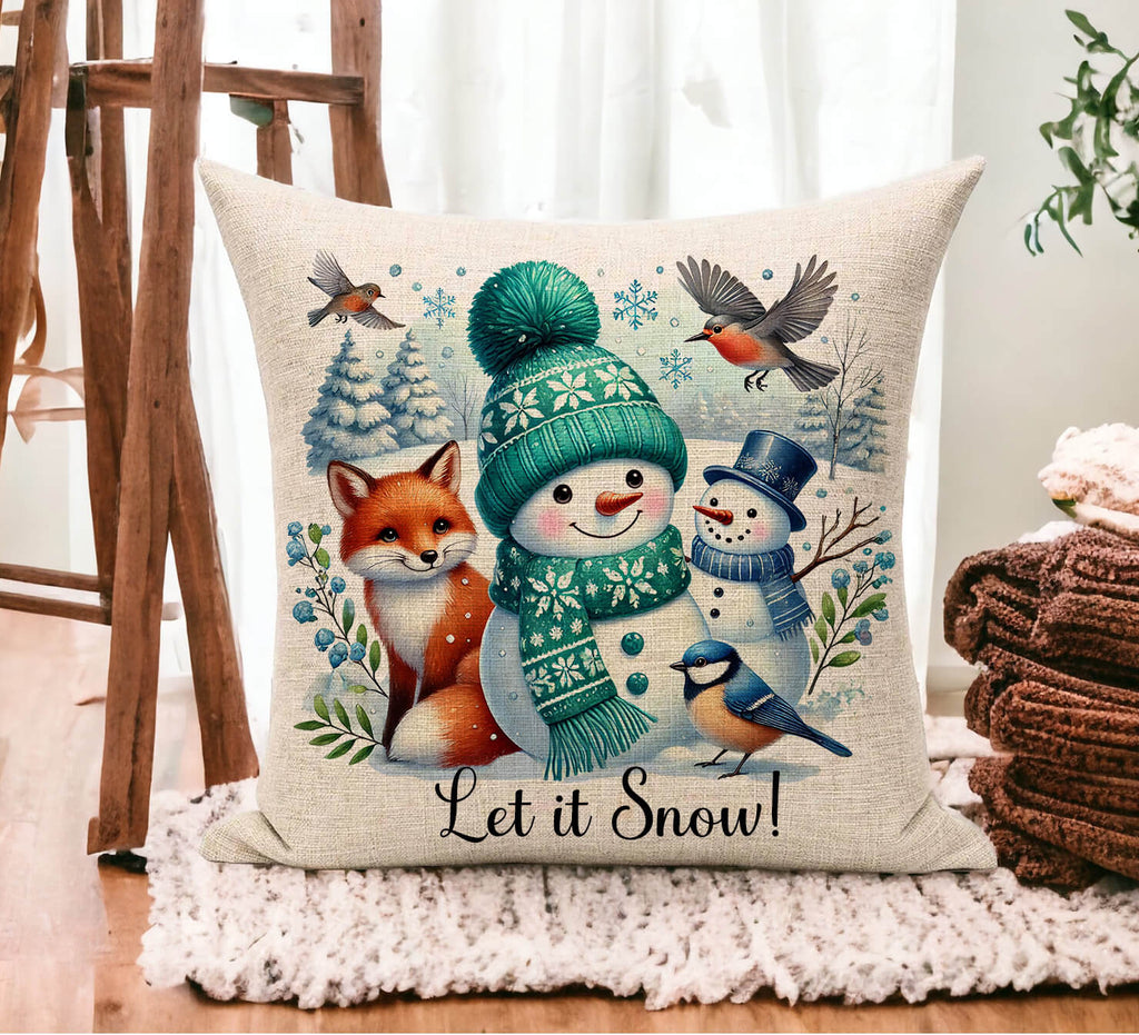 Decorative pillow with winter-themed design featuring a snowman, fox, and birds with 'Let it Snow!' text.